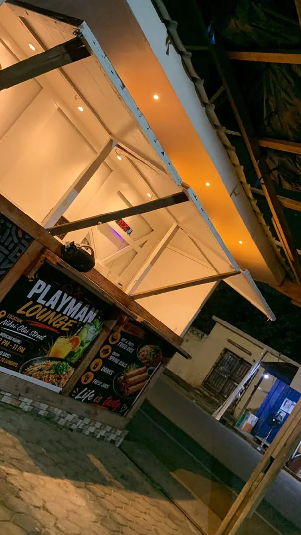 The kiosk lit up at night with the hatch open and the menu board glowing