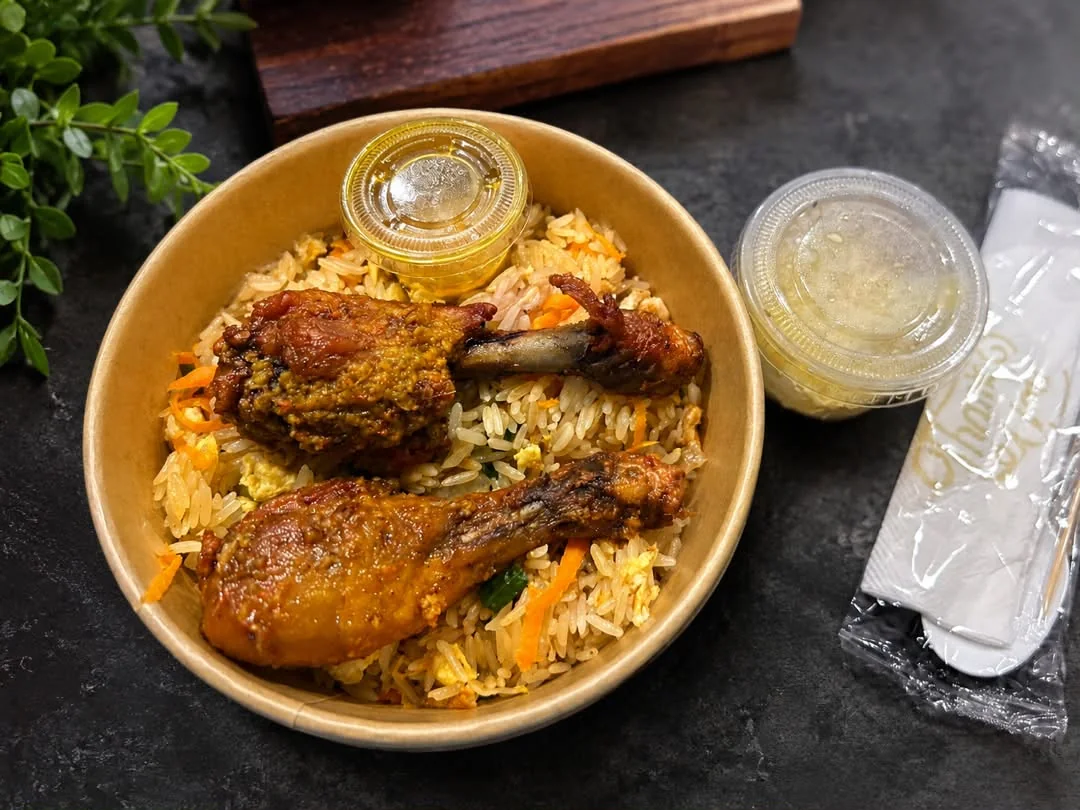Kraft bowl of fried rice with two chicken drumsticks, sauce and wrapped cutlery ready for the rider